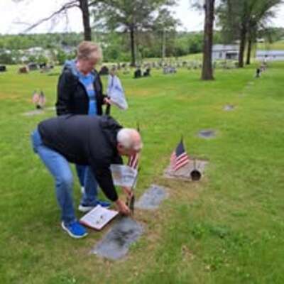 Rotary placing flags on grave markers to recognize deceased members